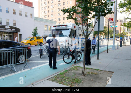 New York, NY, États-Unis. 8 août 2018. La police dirige un cycliste avec une bicyclette électrique de classe 2 -- assistance à l'accélérateur - vers une cage de retenue à côté de la piste cyclable de la deuxième Avenue à Manhattan. Les vélos électriques sont actuellement illégaux dans l'État de New York. Le maire de Blasio de New York a demandé au ministère des Transports de commencer à autoriser les vélos électriques assistés par pédale de classe 1, tout en continuant à faire la répression sur toutes les vélos électriques. La plupart des utilisateurs de vélos électriques sont du personnel de livraison de nourriture. Banque D'Images