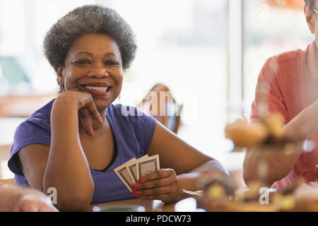 Portrait souriant, confiant senior woman playing cards dans community centre Banque D'Images