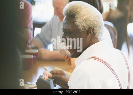 Happy senior man cartes à jouer dans un centre communautaire Banque D'Images