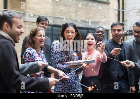 Les amis de célébrer avec woman holding birthday cake Banque D'Images