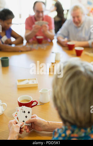 Senior friends playing cards at table in community centre Banque D'Images