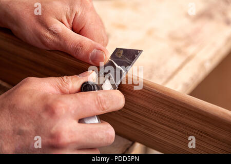 Close-up un charpentier de vêtements de travail de restauration d'un bois avec une spatule sur une table en bois. L'homme travailleur de la construction d'une cale de bois de plâtrage Banque D'Images