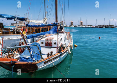 Un voilier amarré dans le vieux port de Rhodes. Dans la distance que vous pouvez voir les trois célèbres moulins à vent Banque D'Images