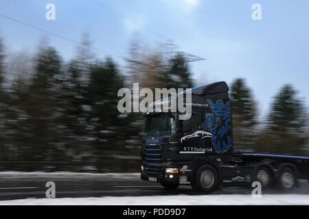 Camion Scania remorque à plateau en tirant sur une route dans des conditions hivernales Banque D'Images