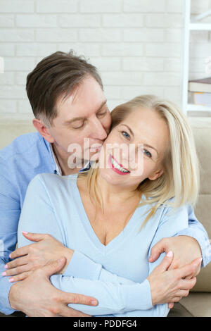 Photo gros plan de joyeux heureux heureux heureux heureux avec dents sourire brillant belle femme blonde et l'homme, il la serre par derrière et l'embrasse Banque D'Images