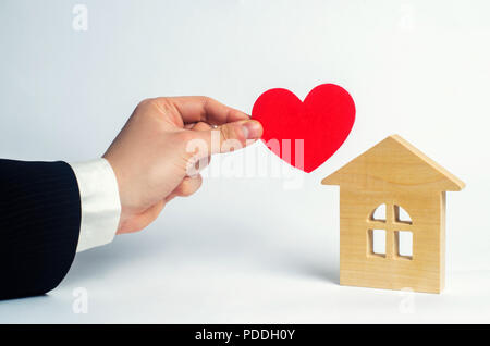 La main de l'homme détient le cœur et la maison . Chambre des amoureux. Logement à prix abordable pour les jeunes familles. Pour les amoureux de couples. Valentine' Banque D'Images