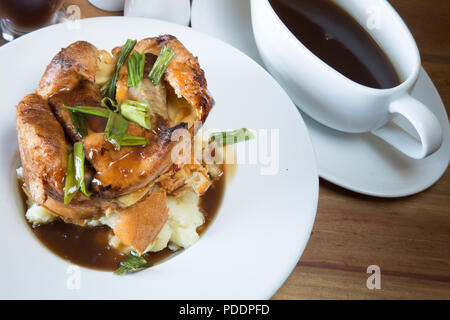 Un pub anglais/restaurant plat de crapaud individuels dans le trou sur un lit de purée de pommes de terre, servi avec sauce brune riche sauce. Banque D'Images