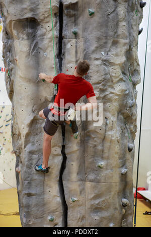 Photo de l'arrière de l'homme grimpant boulder en salle de sport Banque D'Images