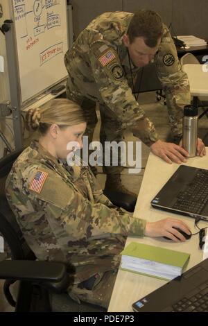 Le personnel. Le Sgt. Stephanie White, un sous-officier du renseignement avec la Garde nationale du Montana montre le Major Mike Talia, le personnel Juge-avocat adjoint de la Garde nationale du Montana, d'une graphique des événements actuels au cours de cyber-protection, mercredi 16 mai au Camp Atterbury, Ind. Cyber Shield 18 Army National Guard est un exercice visant à évaluer les plans d'intervention sur les Guerriers de cyberincidents et dispose de plus de 800 soldats et aviateurs. Banque D'Images