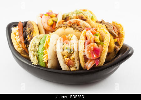 Arepas avec différents fourrages servis dans un plat de céramique noire sur fond blanc Banque D'Images