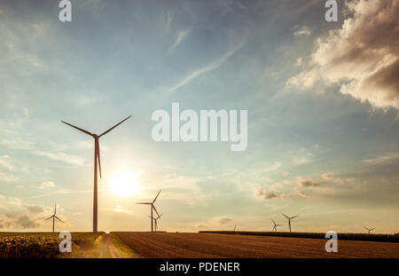 Paysage rural avec des silhouettes d'éoliennes à l'horizon. Banque D'Images