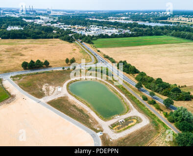 Vue aérienne d'un bassin de rétention de la pluie au bord d'un nouveau développement, pris oblique. Banque D'Images