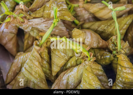 Dessert thaïlandais 'ka-nom-sai-sa j' enveloppées dans des feuilles de bananier avec des feuilles de cocotier longue queue Banque D'Images