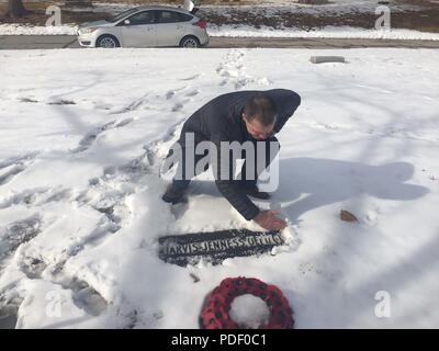 Royal Air Force l'équipage principal, aile Keith 56 Rivet, spécialiste de l'Escadron mixte efface la neige de la 1re Armée américaine tombe du lieutenant Jarvis Offutt Février 2018, à Forrest Lawn Memorial Park, Nebraska. Invité aile le processus d'avoir soulevé la pierre tombale pour faire la pleine inscription lisible. Banque D'Images