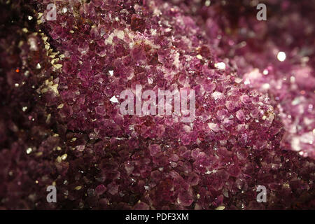 Close up fond de cristaux d'améthyste violet vif lumineux geode allumé dans le noir Banque D'Images