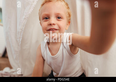 Adorable petit garçon à la caméra et au sourire. Petit enfant a home met la main sur la caméra à l'avant. Banque D'Images