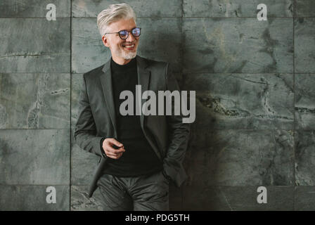 Portrait of smiling senior woman sur mur gris. Handsome businessman looking away et souriant. Banque D'Images