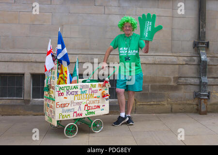 La PRAM homme John un travailleur charité & collecteur pour Macmillan Cancer Support portant une perruque verte et wheeling un landau en bois à Sheffield, Royaume-Uni. Macmillan Cancer Support est l'un des plus grands organismes de bienfaisance britannique et fournit des soins de santé spécialisés, de l'information et de l'aide financière aux personnes touchées par le cancer Banque D'Images