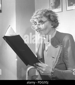 1950s femme avec lunettes. Une dame âgée avec ses lunettes sur le bout de son nez, est en train de lire un document. Suède 1950 photo Kristoffersson/AX40-4 Banque D'Images