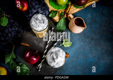 Caramel épicé Apple ou apple pie smoothie, cocktail de fruits d'automne organique avec la crème fouettée, sur un fond sombre, avec les pommes, les feuilles, la sauce au caramel Banque D'Images