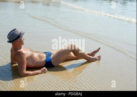 Vie d'été portrait de jeune homme bronzé dans un chapeau. Profiter de la vie et assis sur la plage, le temps de voyage. Face à la mer Banque D'Images