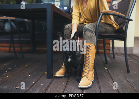 Belle et bonne blonde woman with tablet en bénéficiant d'un café bar avec son adorable bouledogue français. Banque D'Images