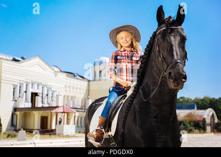 Blonde-haired woman riding horse noir doux Banque D'Images