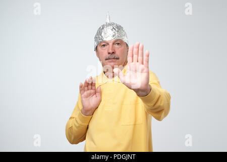 Caucasian man in a tin foil hat déplut à se cacher de la vie en plein air. Peur de l'irradiation ou d'étrangers. Panneau d'arrêt Banque D'Images