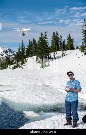 Flying Man emlting quadcopter sur neige et eau de rivière dans le paysage de montagne du nord-ouest du Pacifique Banque D'Images