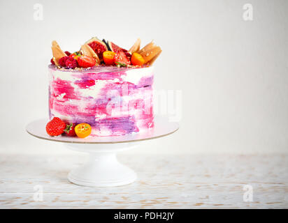 Lumineux magnifique gâteau sur une porcelaine cake stand décoré avec des fruits. Sur le fond blanc Banque D'Images