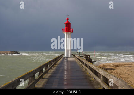 Le phare est peint rouge protégeant le port de Trouville-sur-Mer, Normandie, France avec une tempête venant de derrière Banque D'Images