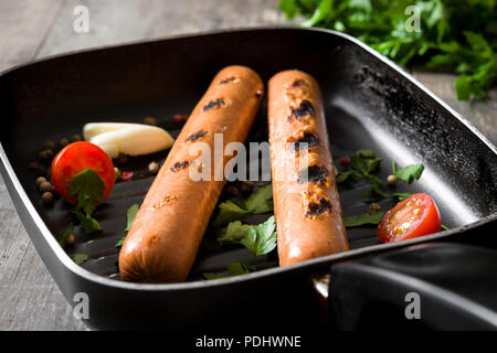 Saucisses grillées dans la poêle de fer sur table en bois Banque D'Images