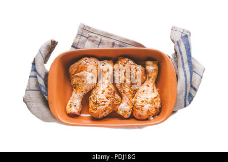 Pilons de poulet crus marinés dans la faïence céramique forme isolé sur fond blanc. Banque D'Images
