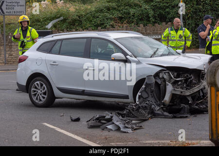 Smashed up estate renault voiture avec le personnel du service d'urgence à l'arrière-plan après une collision frontale Banque D'Images