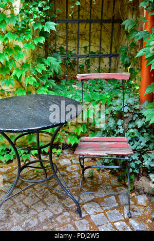 Vieux métal table et chaise par ivy murs patio couvert Banque D'Images