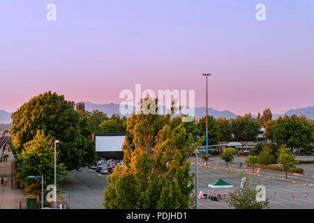 Parking voiture à l'été, cinéma, vert des arbres, montagnes, avion en vol, voitures sur soirée d'été dans la ville moderne Banque D'Images