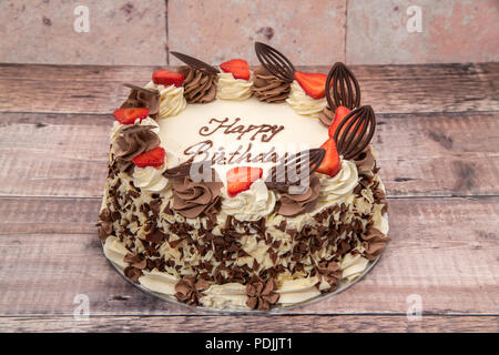 Gâteau d'anniversaire recouvert de crème, fraises et chocolat Banque D'Images