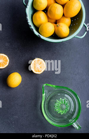 Ensemble et couper les citrons cultivés avec vintage verre vert et centrifugeuse passoire sur fond sombre, vue du dessus Banque D'Images