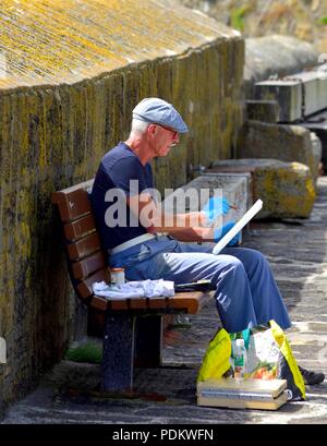 Artiste à la retraite Senior assis sur un banc,Peinture,Angleterre,Cornwall Mousehole,UK Banque D'Images