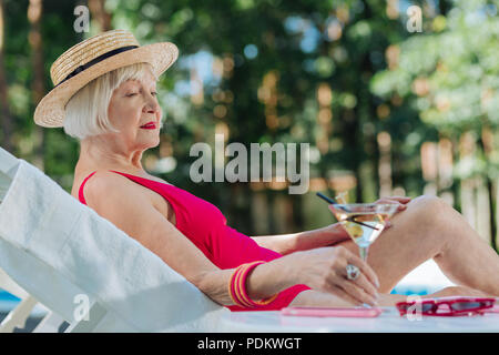 Blonde-haired young woman wearing straw hat situées près de la piscine Banque D'Images