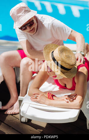 Young woman wearing straw hat lying on deck chair Banque D'Images