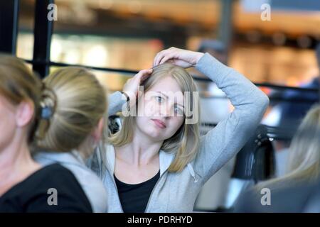 L'aéroport de Schiphol aux Pays-Bas - 3 juillet 2017 : une belle fille blonde dirige sa main dans ses cheveux. Banque D'Images