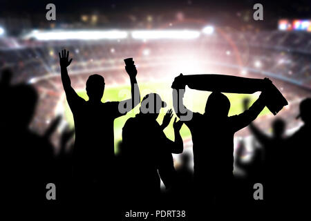 Amis à la partie de football dans le stade de football. Foule acclamer et célébrer un but en arena pendant match. Les gens silhouette dans le sport en direct public. Banque D'Images