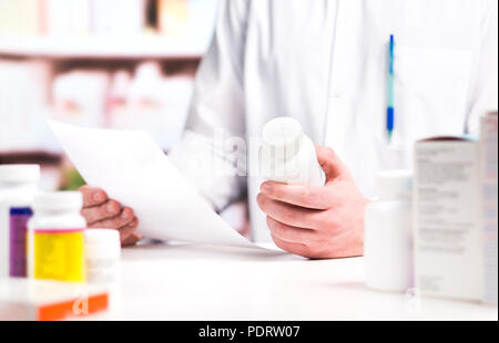 Docteur en médecine de prescription de lecture et bouteille de pilules dans la main en pharmacie. Un professionnel de la pharmacie en vente libre. Banque D'Images