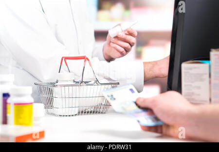 Pharmacien et le client au comptoir de la pharmacie. De l'achat de médicaments du patient et donner de l'argent. Pharmacien et une caisse à l'aide de la caisse enregistreuse. Banque D'Images