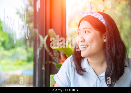 Cute Asian chubby gras dodu jeune adolescente sourire à Windows Banque D'Images