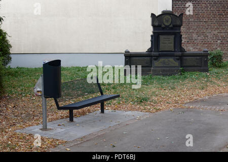 Banc avec poubelle à côté d'une pierre tombale dans l'ancien cimetière protestant, Velbert, Allemagne. Banque D'Images