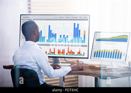 Young Businessman Looking At graphique sur les ordinateurs de l'Office Banque D'Images