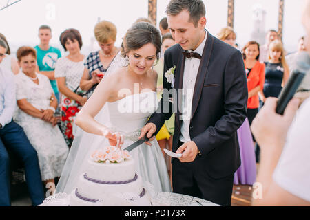 Vue rapprochée de la coupe senior couple leur premier morceau de gâteau de mariage. Banque D'Images