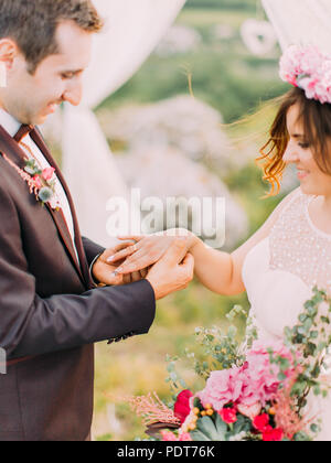 Vue rapprochée de l'époux de mettre l'anneau de mariage sur les mains de la mariée lors de la cérémonie de mariage. Banque D'Images